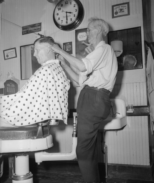 Emelius A. Sorenson, a partner in the Sorenson and Gruenberg Barber Shop at 854 Williamson Street, uses a chair that attaches to the barber chair. He says he hasn't had any trouble with his legs and feet since he started using the device five years ago.