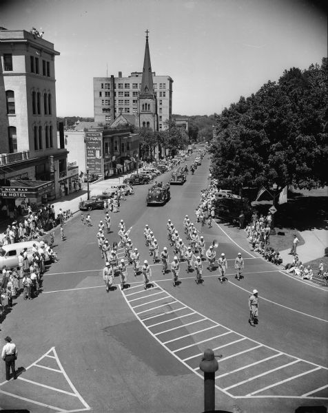 Elevated view of the 504th Air Force band from Truax Field leading off the 1952 Fourth of July parade followed by two of Madison's newer fire trucks. The view is on the Capitol Square, with the Park Hotel on the left, and Grace Episcopal Church. East Side Businessmen's Association parade.