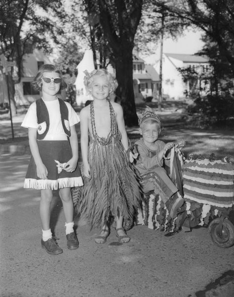 Three children are dressed in costume for the children's parade during the Virginia Terrace 4th of July neighborhood celebration. Left to right: Susan Bucchel, dressed as a cowgirl, Barbara Teasley in a skirt made of fern leaves, and John Brown as an Indian.