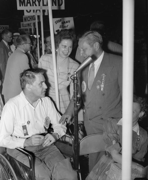 Harlan W. Kelley of Baraboo, is disabled. He is the Sauk County district attorney, and talks with Cyrus L. Phillips of Milwaukee at the Republican National Convention in Chicago. Mrs. Kelley looks on.