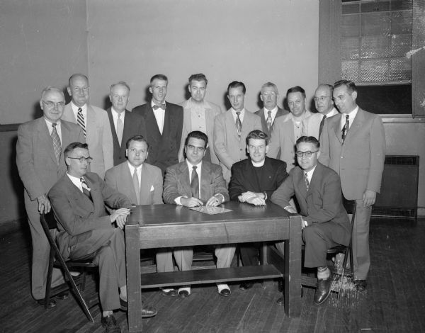 Group portrait of the new officers of the Madison Knights of Columbus. Shown seated left to right are: James J. McNally, chancellor; Dr. Don Bergenske, deputy grand knight; Vincent F. Deppisch, grand knight; the Rev. Jerome J. Mersberger, chaplain, and Leonard J. Wagner, warden. Standing, left to right, are: J. Vincent Conlin, Edward J. Owens and L. Matthew Larson, trustees; Louis F. Genter, advocate; George Stein, district deputy; Joseph Vaughan, lecturer; John Sheehan, outside guard; Herman Kleinheinz, financial secretary; W.F. Handell, treasurer, and Caspar LaVeer, guard.