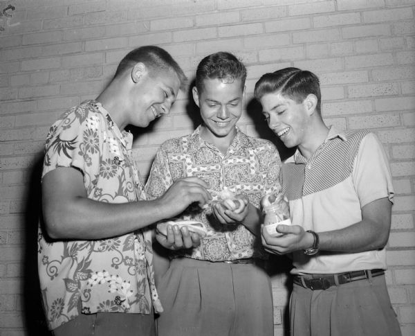 Left to right, Robert Morgensen, Roger Mayer and Bronson La Follette eating hot dogs during the Mendota Yacht Club moonlight regatta and picnic supper on the roof of the Edgewater Hotel.