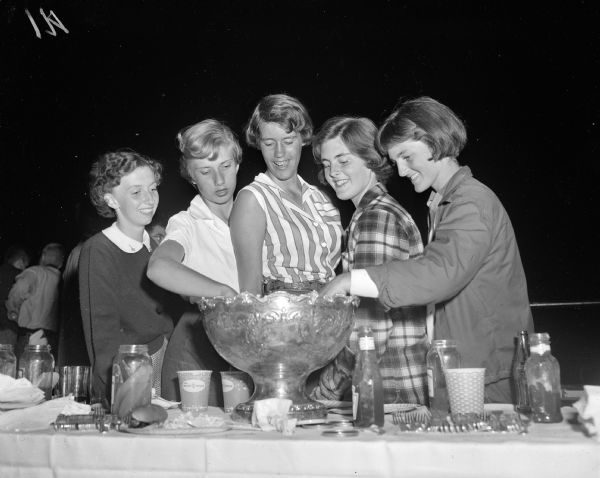 Nancy Castle (left), Mary Meyer, Kathie Manchester, Rosanne Bothan, and Betty Lou Botham stand at the refreshment table during the Mendota Yacht Club moonlight regatta and picnic supper.