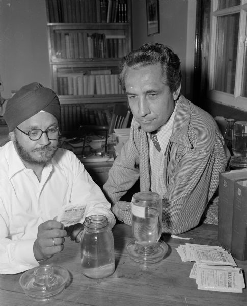 Dr. Karl Paul Link, professor of biochemistry at the University of Wisconsin, right, is pictured with Dr. Mohan Singh, director of food preservations for the government of India and on a United Nations mission, at left, who is visiting Dr. Link to learn about the rat killer Warfarin, invented by Link. India is greatly troubled by rats eating food and grain received in India under the Marshall Plan.