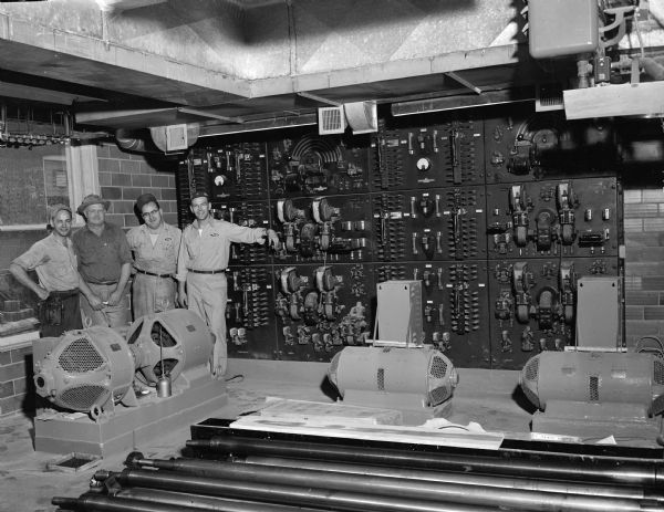 Four staff members and view of the switchboard wall that operates the presses at the offices of the Wisconsin State Journal, Madison Newspapers, Inc., 115 South Carroll Street.