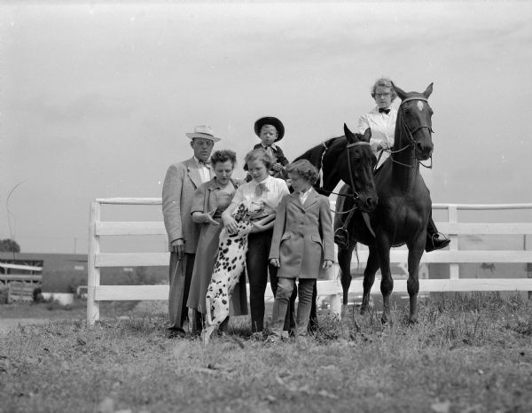 The Maurice and Trudy Klinke family and their horses. Standing left to right: Mr. and Mrs. Klinke, and children Nancy and Patsy with their Dalmatian coach dog. Son Jimmy is sitting on "Ebony," and daughter Lois is on "Major." They will compete in the Madison Saddle Club Horse Show.