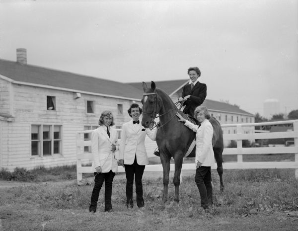 Entered in the English saddle class in the Madison Saddle Club horse show are, left to right, Ann Ladd; Donna Wartner; Jinny Waartner, sitting on a horse; and Nancy Ladd.