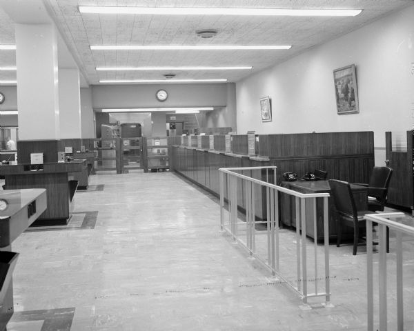 Interior of the newly enlarged and redecorated Madison Bank and Trust Company, 23 W. Main Street. There are teller stations along the wall, and railed-off space for executive's desks.