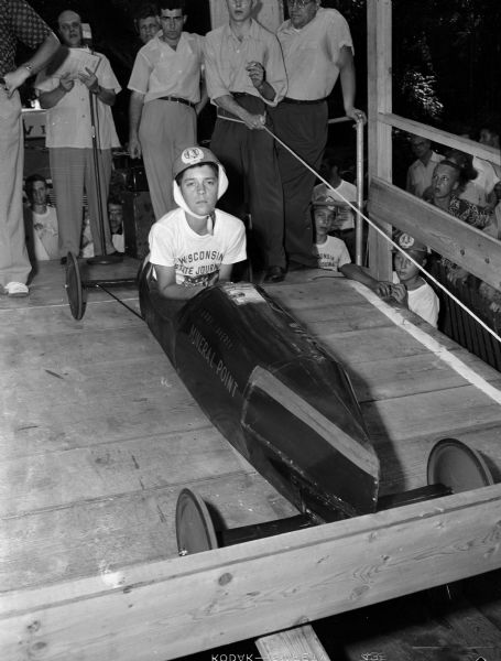 Larry Laverty, a Mineral Point farm boy and the champion of the Madison Soap Box Derby, sits in his racer. He will go to Akron, Ohio to compete in the All American Derby.