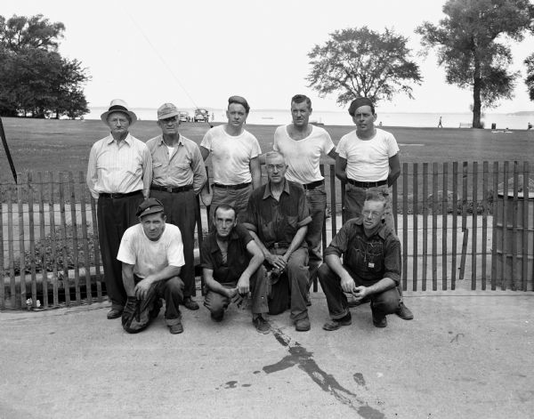 Group portrait of nine Madison street department workers who have prepared the derby hill for the Soap Box Derby for the past seven years. Kneeling, left to right, are: Ray Wolder, Les Conners, Walt Brussow, and Ellis Hornbeck. Standing, left to right, are: Jim Shell, Vince Sullivan, Warren Kimberly, Floyd Klitzman, and Earl Ulsrud.