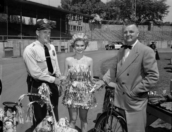 Fourteen-year old Darlene Kripps, center, is the winner of the award for best costume and decorated bike in the Bicycle Safety Week parade. Standing at her left is Ben Precourt, safety director of the American Automobile Association Madison. Police chief Bruce Weatherly, at her right, acted as the parade marshal and  also was a judge of the competition.
