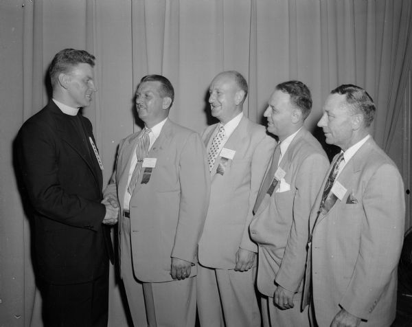 The Reverend Jerome Mersberger (at left), pastor of the Immaculate Heart of Mary Catholic Church, is honored at the annual convention of the Wisconsin Moose Association. Pictured with the priest are, left to right: C.H, Showers, governor of Madison Lodge #1451; Edward J. Owens, chairman of the convention; Elmer N. Stubner, state president of the Wisconsin Moose association; and Roy E. Wing, Wisconsin state director of the Loyal Order of the Moose.