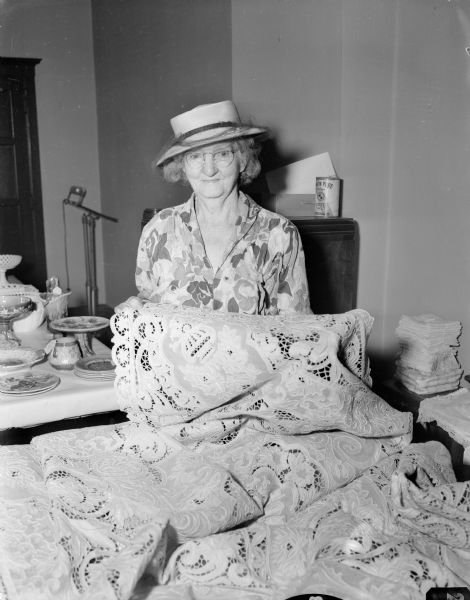 Mrs. Frank Vaughn holding a cut work tablecloth at the sale of the late Miss Catherine Corscot's antique collection. It was held in the Guild Hall in Grace Episcopal Church.