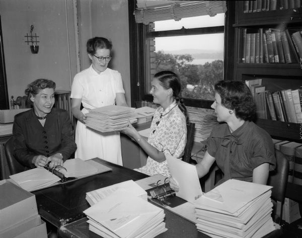 "Assisting in the compiling of reference notebooks for prospective nurses are the four wives of doctors pictured above. From left to right, they are Mrs. O. Sidney Orth, Madison, a director of the board of the State Medical society auxiliary; Mrs. Adolf Soucek, Madison, press and publicity chairman for the state auxiliary and a member of the Dane County Medical society auxiliary; Mrs. Victor S. Falk, Jr., Edgerton, head of the nurse recruitment committee for the State Medical auxiliary, and Mrs. George Thomson, Beloit, a member of the Rock County Medical auxiliary.  The notebooks will be distributed to Wisconsin's 480 secondary schools."