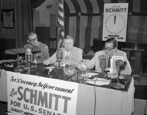 Leonard F. Schmitt, Merrill attorney who is challenging U.S. Senator Joseph B. McCarthy for the Republican nomination in the primary, is pictured half-way through his 25-hour radio talkathon. Schmitt, center, is flanked by Micheal Griffith, left, former Madison newsman and manager of his campaign, and Pat Hernon, Madison announcer for radio station WKOW.