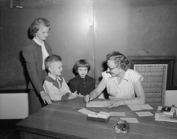 Three of the 185 pupils who registered at Madison Lutheran school are shown with Esther Buehholz (right).  Left to right are Patricia Hagen, 12,  Dickie Baer (wearing a cowboy shirt), 6, and Marcia Thompson, 6.