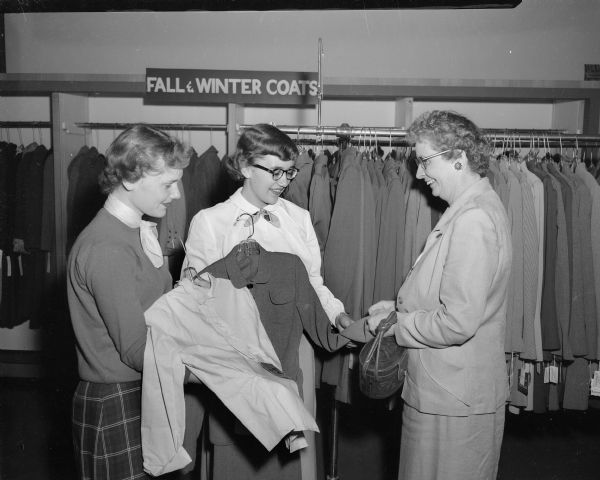 Two Madison girls work summer jobs as sales clerks. They are Sue Giese of 4010 Saint Clair Street, left, and Barbara Thalle of 2249 Fox Avenue. They are 1952 graduates of West High School. The customer is Catherine Barry of Oregon.