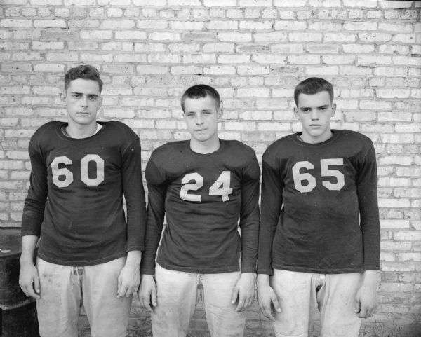 Group portrait of three uniformed Edgewood High School football players. Shown, left to right, are: Duane Fose (#54), Wayne Slightam (#24), and Ed Zevnik (#65).
