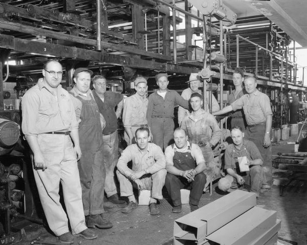 Group portrait of the printing press staff in the press room at the Wisconsin State Journal offices.