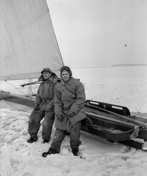 Jim Lunder and another man dressed in heavy winter clothing sit on the iceboat "Fritz" on frozen Lake Monona (?).
