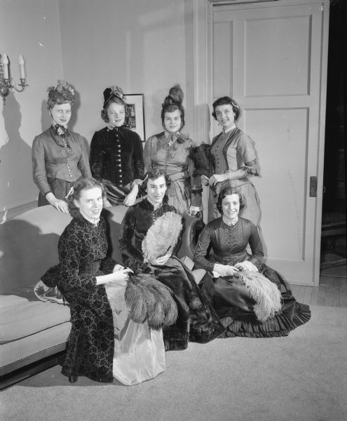 Portrait of a group of University of Wisconsin Pi Beta Phi initiates taken at the Founder's Day banquet. The women are in costume dress related to a skit presented at the banquet. Shown seated, left to right, are: Betsy Griem of Madison, Judy Otto of Madison, and Shirley Capitani of Highwood, Illinois. Standing, left to right, are: Sue Benson of Appleton, Barbara Gariepy of La Grange, Illinois, Constance Leahy of Stevens Point, and Virginia Watson, of Evanston, Illinois.