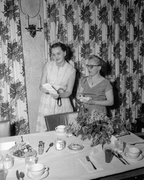 Ethel H. Martin, left, secretary of the Cosmos Dance Club, and Hazel M. Hofsteen, right, wife of the club treasurer, consult over the arrangement of place cards at the club's 30th anniversary dinner dance held at the Nakoma Country Club.