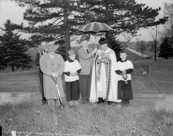 Ground breaking ceremonies at the site of St. Mary of the Lake Catholic Church to replace the church that was destroyed by fire in 1951. The Reverend Edward B. Auchter, the present pastor of the parish, is shown conducting the service. Also in the group portrait, left to right, are: Peter Hornung, parish secretary; Arthur O'Keefe, parish treasurer; James Capaul, an altar boy; Louis Siberz, architect; and Robert Tierney, an altar boy.