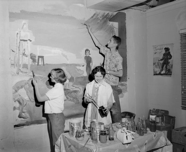 Water safety accident prevention and first aid are the themes of the mural being completed by East Junior High School pupils for the east wall of the Junior Red Cross assembly room, 302 East Washington Avenue. From left, the artists are: Virginia Stroede, Connie Zimmerman, and Ronnie Adler.