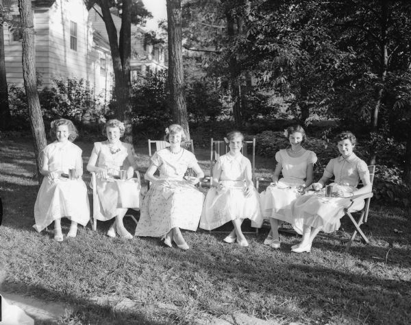 Six Nakoma School graduates sitting outdoors during a buffet supper at the John C. and Ida Doerfer home at 4105 Chippewa Drive. Left to right: Georgiana McBurney, Judy Smith, Marsha Shaeffer, Nancy Henderson, Judy Fett, and Clarice Grosenick.