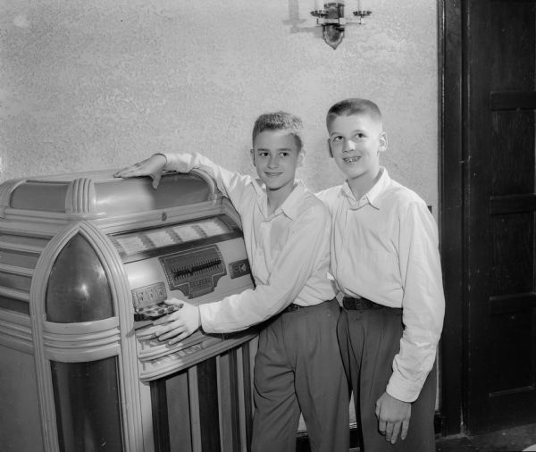 Dick Guerny, left, and Gordon Doefer, Nakoma School eighth grade graduating students, stand next to a jukebox during a dance at Nakoma Country Club.