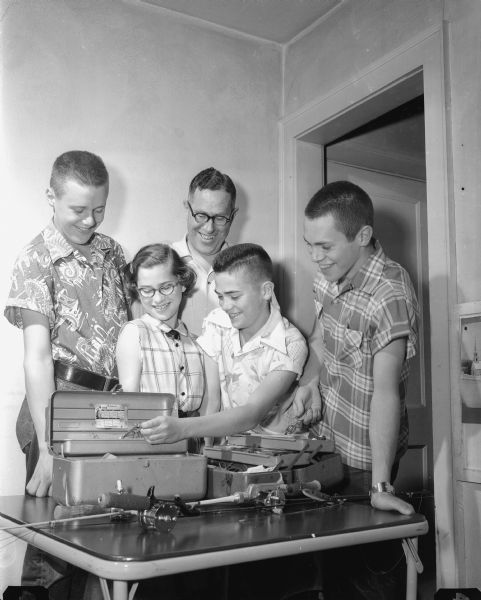 A photographic tribute to Madison dads on Fathers Day includes a portrait of Madison City Engineer John G. Thompson and his three sons, Jim Thompson, Douglas Thompson, and Tom Thompson, and one daughter Margaret Thompson. They are shown inspecting fishing tackle.