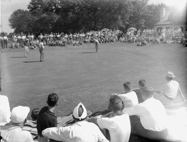 Finish of the final foursome, Frank Parkinson, Steve Caravello and Walter Atwood, on the 18th green of the Nakoma Golf Course, with crowd.