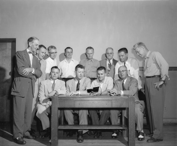 The twelve members of the Zor Shrine - Knights of Columbus Softball Extravaganza Committee are shown around a table planning their parade and show, proceeds from which are given to charity.