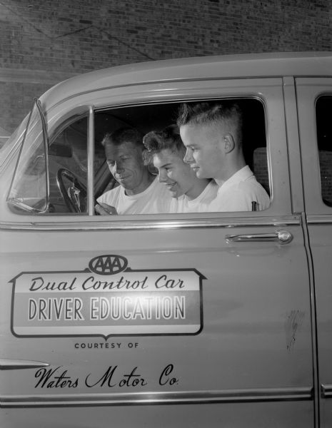 Seated in a dual control car used for driver education classes are, from left: Milt Diehl, instructor, and East High students, Bruce Schmidt and John Fillhouer.