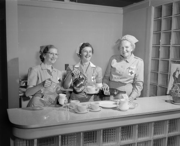 Three volunteers for the American Red Cross, Dane County branch, take a break at the snack bar. Shown left to right are: Mrs. T.H. (Mary) Ellison, Mrs. B.L. (Myrna) Brindley, and Mrs. C.O. (Christine) Everson.