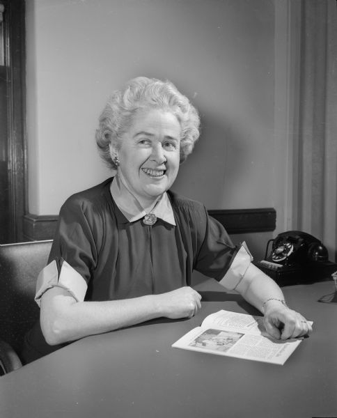 Portrait of Rebecca Chalmers Barton, Director of the Wisconsin Governor's Commission on Human Rights, seated at her desk.