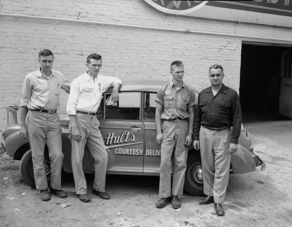 Portrait of four employees of Hult's Garage who will be in charge of transporting soap box derby racers and returning vehicles after the race. Left to right: Bob Whipple, Ralph Hoffman, Lowell Hammer, and George Lambrecht.