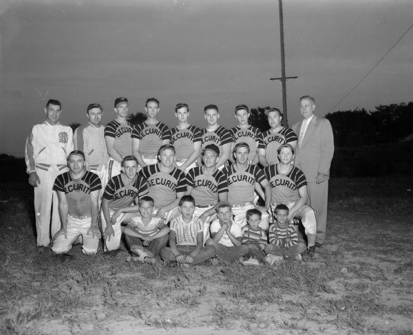 Group portrait of the softball team of Security State Bank. They played in a Kiddie Camp benefit at Breese Stevens Field. Shown left to right in the back row are: F.J. (Kutch) Koovara, Roland (Zeke) Johnson, Don Page, Cletus Casey, Ray Kelly, Joe Meyers, Arnold (Cobby) Schmale, and Ray Bennett.  Shown left to right in the front row are: Bob Goodman, Orv Storek, Orval Austin, Jr., Dick Havey, Ed Kotecki, Les French, Joe Leiberman, and Fred Fuller. Koovera and Bennett are the team managers.