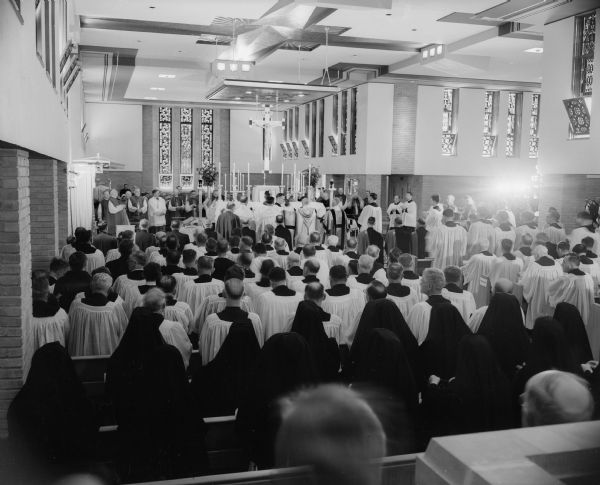 The Most Rev. William P. O'Connor of Madison stands at the center of the altar during the Mass at Saint Coletta school in Jefferson following the blessing of the school's new chapel by Samuel Cardinal Stritch of Chicago. The honor guard of Knights of Columbus, priests of the diocese, and some of the Franciscan nuns who teach at the school are shown in the foreground. The cardinal stands near his throne at the left.