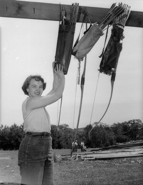 Marjorie Smith is selecting a loaded quiver at the Blackhawk Bowhunters Club. A group of people are standing in the far background.