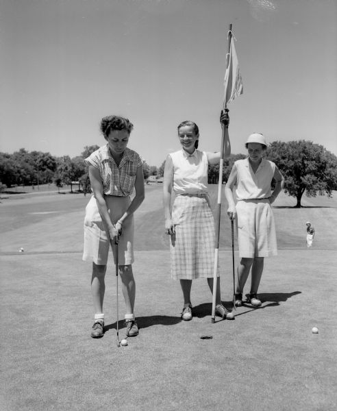Three golfers on a green at the Maple Bluff Country Club during the women's inter-club golf match. Left to right are Sally Littig of Blackhawk, Alice Dean of Maple Bluff, and Lora Kurtz of Nakoma.
