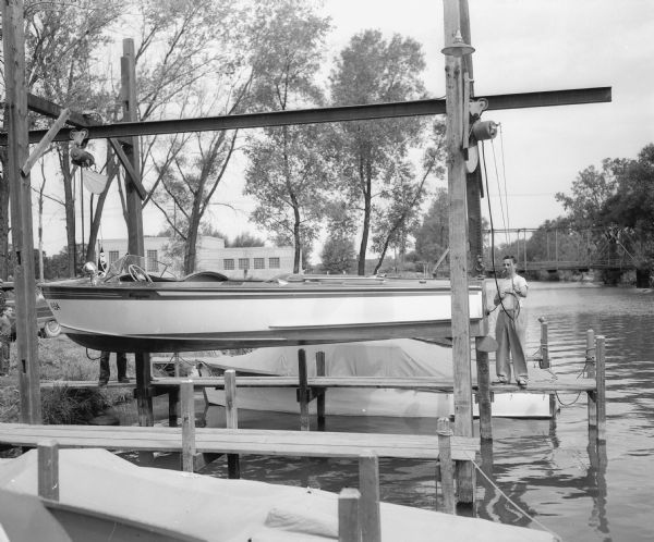 Four Lakes Yacht Club member Clair Puttkamer is shown with his boat on a hoist operated by the Four Lakes Yacht Club on the Yahara river. The hoist facilitates the inspection, repair and storage of yacht-size crafts.