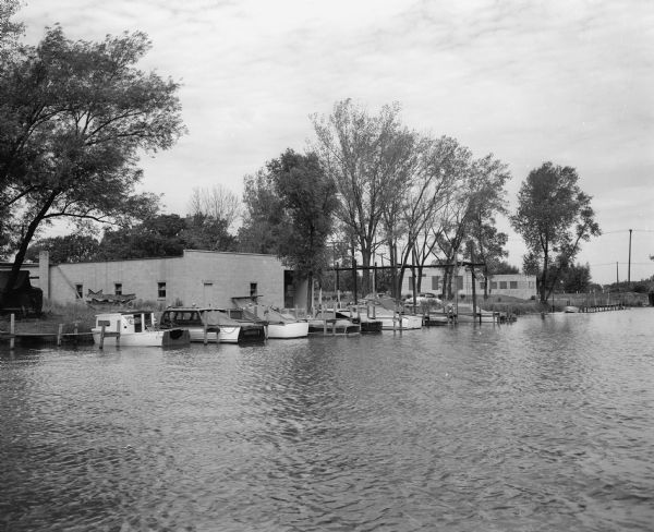 The club house of the Four Lakes Yacht Club, situated along the Yahara River with boats tied up along the slips.
