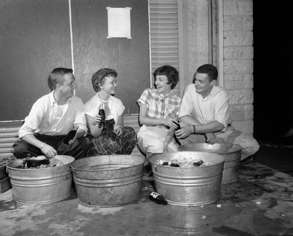 Sitting next to wash tubs filled with ice and bottles of soft drinks at the Mendota Yacht Club beachcombers party are, left to right: Tony Stebbins, Ann Battles, Jeri Briggs, and Bill Bush.