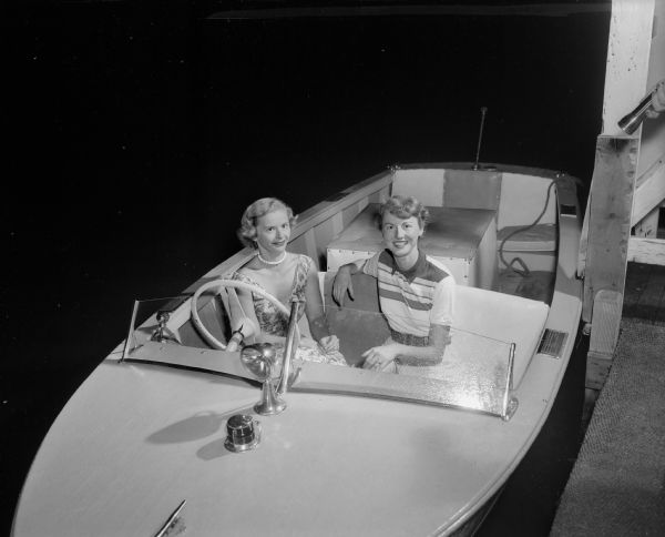 Seated in the front seat of a motor boat are Phyllis Beck, left and Barbara Johnson. They are attending the Mendota Yacht Club beachcombers party at the Maple Bluff swimming beach.
