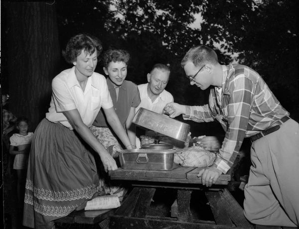 Four members of the Philharmonic Chorus at a picnic table at their annual picnic. Shown left to right are: Mrs. Ruth (Robert M.) Foster, Mrs. Catherine McCloskey, David Eising, and George Socha.