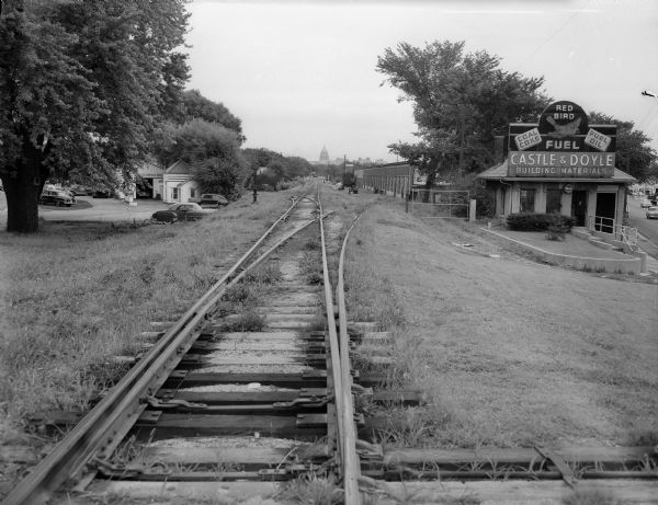 Illinois Central railroad tracks at Monroe Street Castle & Doyle Building at Monroe and Regent Street intersection at 1512 Regent Street. The Wisconsin State Capitol rotunda is visible at center on the horizon.