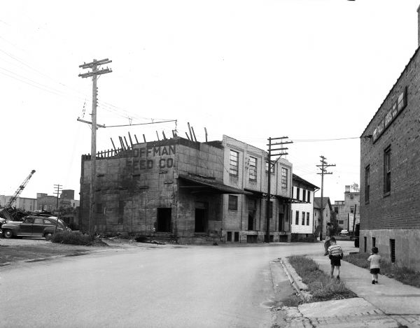 Children walking along the sidewalk near the Hoffman Feed Company building, 503 Regent Street, which is being torn down to widen the street at the intersection of West Washington Avenue.