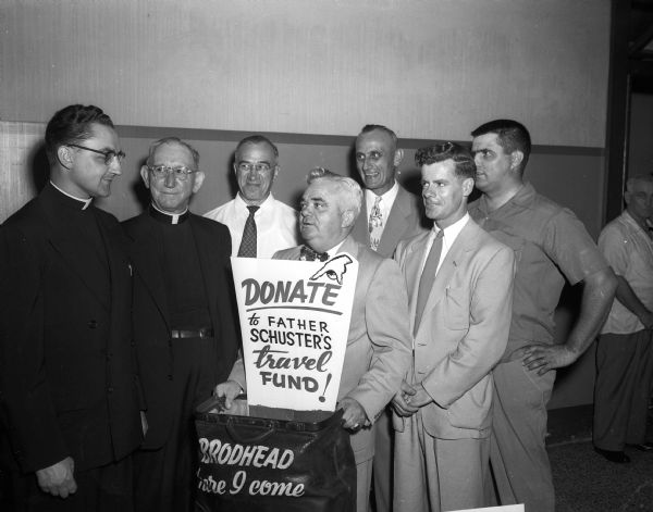 Members of St. James Catholic parish, including Reverend John A. Koelzer, Rod Nilles, Sheriff Franz Haas, Joe Soehnein, Walter F. Kearns and Mike Marinac(?), honor Reverend Wilford Schuster on the eve of his departure for a new assignment in Brodhead, Wisconsin.