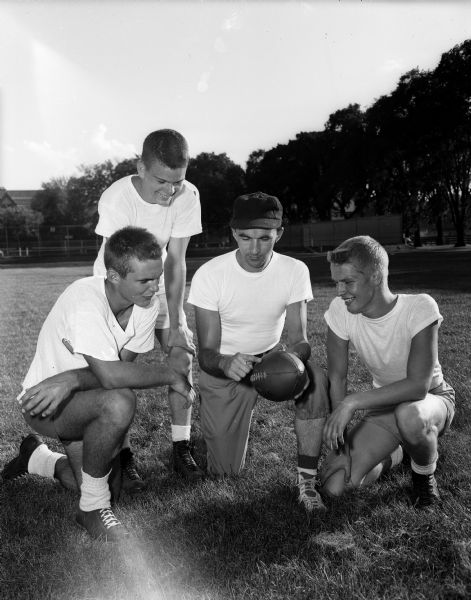 Wisconsin High School coach Hal Metzen poses on the University intra-mural field with three of his nine lettermen: Jim Schneiders, Doug Angevine, and Fred Willadsen.